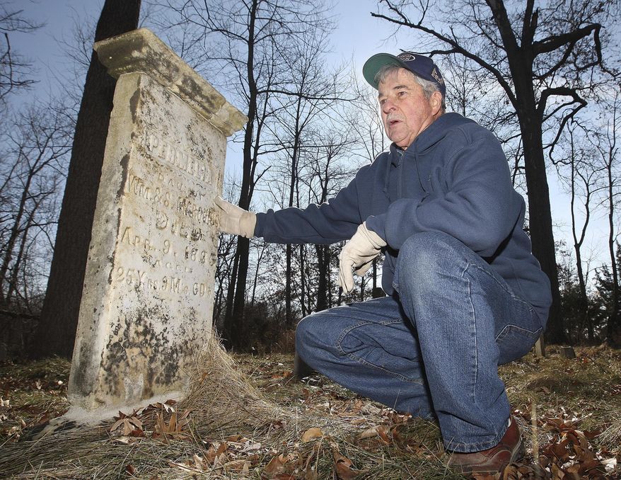 ADVANCE FOR USE SATURDAY, FEB. 28 AND THEREAFTER - In this Jan. 28, 2015 photo, John Heider of Monticello, Ill., who created a business called R.I.P., Ltd. that restores gravesites and cemeteries, kneels by a tombstone he uncovered at the Barnes Cemetery near Monticello, Ill. (AP Photo/Herald & Review, Jim Bowling)