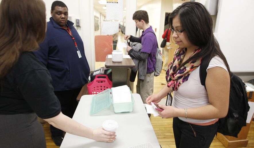 Teacher Monica Iliff hands off a hot chocolate for Crystal Rodriguez at the East Daily Grind, the student run coffee shop at East High School in Waterloo, Iowa, Thursday, Feb. 12, 2015. The coffee shop which opened a little over a month ago, offers coffee, tea, hot chocolate and several flavors of cappuccino to students and staff looking for a warm pick-me-up. (AP Photo/The Courier, Brandon Pollock)