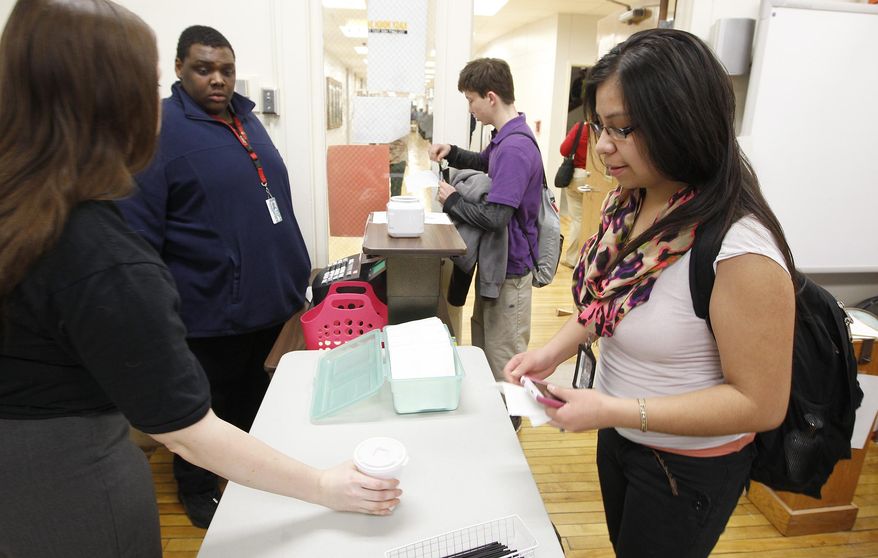 Teacher Monica Iliff hands off a hot chocolate for Crystal Rodriguez at the East Daily Grind, the student run coffee shop at East High School in Waterloo, Iowa, Thursday, Feb. 12, 2015. The coffee shop which opened a little over a month ago, offers coffee, tea, hot chocolate and several flavors of cappuccino to students and staff looking for a warm pick-me-up. (AP Photo/The Courier, Brandon Pollock)