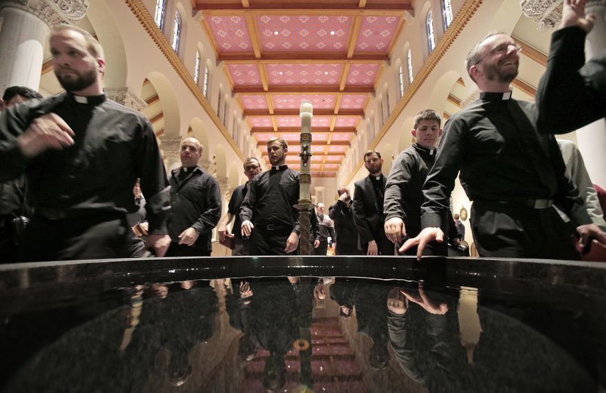 In this Feb. 10, 2015 photo, seminarians and faculty leave afternoon prayer service, dipping their fingers in holy water and making the sign of the cross, in the chapel of The Saint Paul Seminary School of Divinity in St. Paul, Minn. Faced with a surging number of seminarians, the Madison Catholic Diocese is turning to its parishioners to help fund the training of priests. (AP Photo/Wisconsin State Journal, M.P. King)