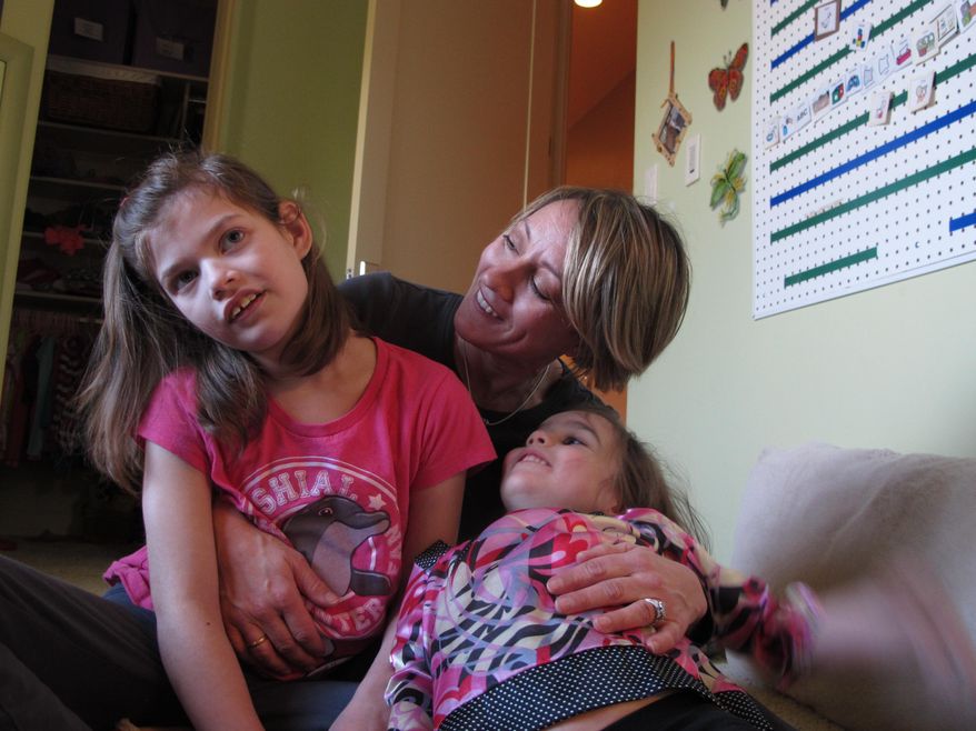 Alexis Carey, left, 10, sits with her mother Clare Carey, center, and her sister Alanis Carey, right, 5, on Friday, Feb. 27, 2015, in Boise, Idaho. Alexis has a rare form of epilepsy, however, her family is hoping the Idaho Legislature will decriminalize marijuana extract oil to help reduce her seizures. The family began lobbying lawmakers to decriminalize the oil almost two years ago. Now, they’ve got some legislative backers and an upcoming hearing, as Idaho joins a larger movement to loosen laws to allow the use of marijuana extract oil. (AP Photo/Kimberlee Kruesi)