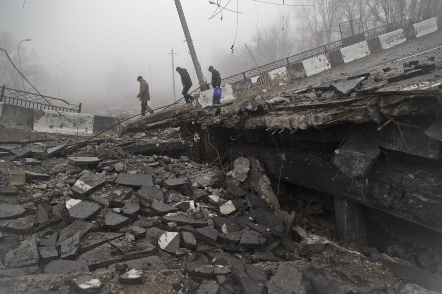Men across a destroyed bridge, fallen onto the road towards the airport, the scene of heavy fighting in Donetsk, Ukraine, Sunday, March 1, 2015. The recent pullback of some weapons from the line separating government and rebel forces in Ukraine seems to have boosted the prospects for peace, although both sides are warning of their readiness to resume fighting if necessary.(AP Photo/Vadim Ghirda)