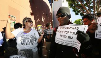 Suzette Shaw, left, a homeless woman, joins others protesting a police shooting of a homeless man on Tuesday, March 3, 2015, in downtown Los Angeles. There was a moment of silence at the site of the shooting where several dozen people rallied Tuesday in protest. (AP Photo/Nick Ut) ** FILE **