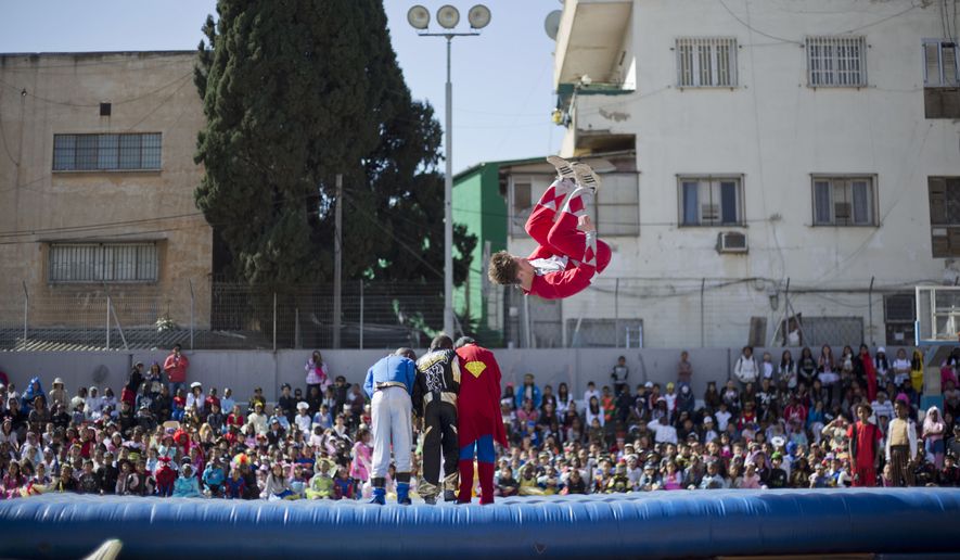 Acrobats performs for children of foreign migrant workers during a Purim party in Tel Aviv, Israel, Tuesday, March 3, 2015. The Jewish holiday of Purim commemorates the Jews' salvation from genocide in ancient Persia, as recounted in the Book of Esther, which is read in synagogues. Other customs include: sending food parcels and giving charity; dressing up in masks and costumes; eating a festive meal; and public celebrations. (AP Photo/Ariel Schalit)