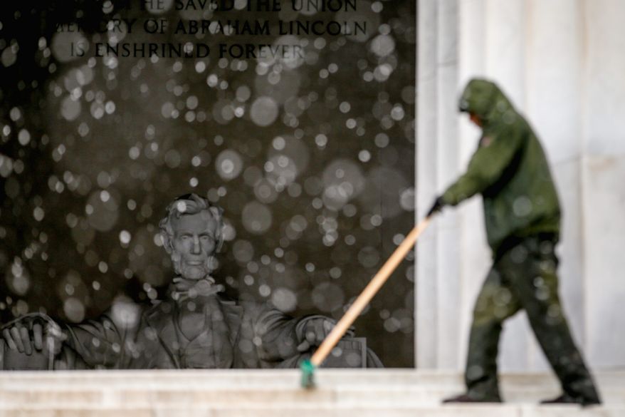 U.S. Park Service maintenance supervisor sweeps snow off stairs at the Lincoln Memorial with the statue of Abraham Lincoln visible in the background on Thursday. As much as 9 inches of snow blanketed the greater D.C. area on Thursday. The National Weather Service has forecasted temperatures in the 50s next week. (associated press)
