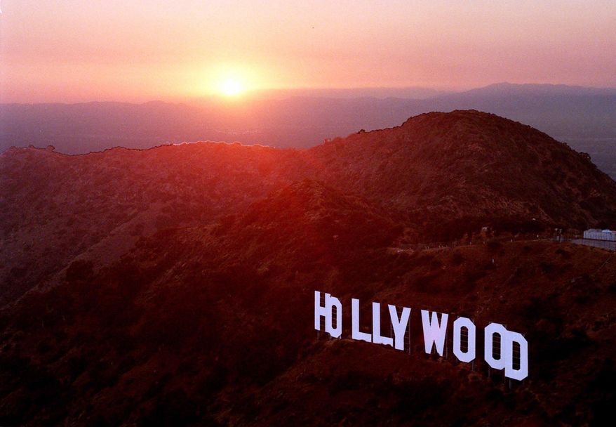FILE- This June 30, 1999 file photo shows the sun setting behind mountains as the Hollywood sign overlooks Los Angeles. For a century and a half California has been a destination for every conceivable sort of adventurer. (AP Photo/Reed Saxon, File)