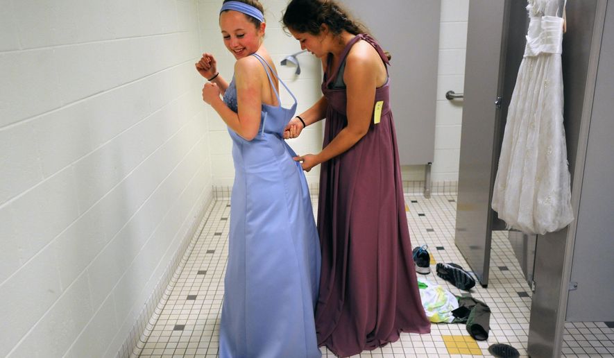 Community High School junior Eliza Upton helps Ann Arbor Huron junior Tulin Babbitt get into a gown at a $20 prom dress sale at Huron High School, in Ann Arbor, Mich., on Friday, April 25, 2014. The annual Prom Dress Project offers dresses for girls at an affordable price. (AP Photo/The Ann Arbor News, Brianne Bowen)