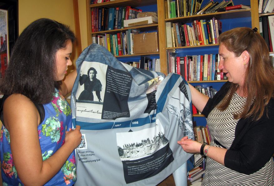 In this March 4, 2015 photo, University of South Carolina student Britney Ghee, left, and Professor Allison Marsh, discus a banner at the University of South Carolina in Columbia, S.C. They are taking several of these banners with them on a study trip to Guantanamo Naval Base in Cuba from March 6 to March 13, 2015. Marsh is leading her graduate history students as part of a national effort to gather historical information about people who live and work on the installation. (AP Photo/Susanne Schafer)