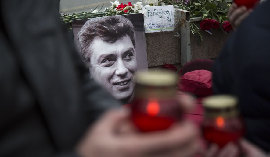 In this file photo from March 7, 2015, mourners are shown following the Russian tradition of memorializing a person nine days after a death lay flowers and votive candles at the place where Boris Nemtsov, a charismatic Russian opposition leader and sharp critic of President Vladimir Putin who was gunned down on Friday, Feb. 27, 2015 near the Kremlin, in Moscow. On Feb. 27, 2018, the street outside the Russian Embassy in Washington, D.C. was officially renamed in Nemtsov's honor. (AP Photo/Alexander Zemlianichenko) **FILE**
