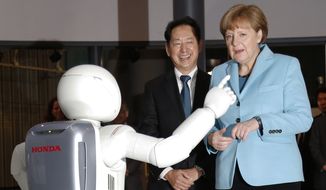 German Chancellor Angela Merkel, right, watches Honda Motor Co.&amp;#8217;s interactive robot Asimo demonstrate, along with the National Museum of Emerging Science and Innovation &quot;Miraikan&quot; Chief Executive Director Mamoru Mori during her visit to the the museum in Tokyo, Monday, March 9, 2015. Merkel is in Japan on Monday and Tuesday as part of a series of bilateral meetings with G-7 leaders ahead of a June summit in Germany. (AP Photo/Shizuo Kambayashi)