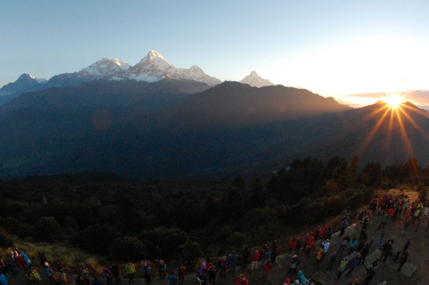 In this Friday, Oct. 24, 2014, photo, the sun rises above the Annapurna Range in central Nepal as viewed from Poon Hill, above the village of Ghorepani. Poon Hill, the highest point of the six-day, 65-kilometer (40-mile) loop through the villages of Ghandruk and Ghorepan can be crowded with other trekkers at sunrise during peak trekking season. (AP Photo/Malcolm Foster)