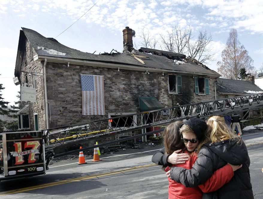 As firefighters and officials investigate an overnight fire that destroyed The Sergeantsville Inn Monday, owner Lisa Clyde, left, is hugged by neighbors March 9, 2015, in Delaware Township, N.J. The fire destroyed the historic New Jersey inn that once hosted George Washington. (AP Photo/Mel Evans)