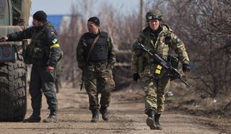 Ukraine servicemen walk at a front-line position east of Mariupol, Tuesday. President Obama has not ruled out providing defensive weapons, but administration officials offered no clue on when Mr. Obama might make a final decision. (Associated Press)