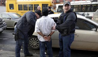 In this March 3, 2015 photo, Immigration and Customs Enforcement officers make an arrest in New York, during a series of early-morning raids. Immigrant and Customs Enforcement say an increasing number of cities and counties across the United States are limiting cooperation with the agency.  (AP Photo/Richard Drew)
