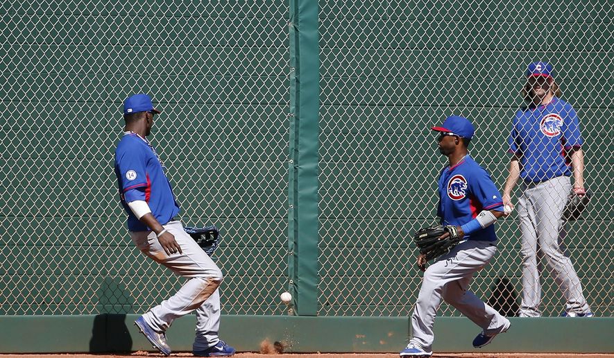 Chicago Cubs&#39; Junior Lake, left, and Arismendy Alcantara are unable to track down a ball hit by Cleveland Indians&#39; Carlos Santana as it falls between them, as Cubs&#39; pitcher Pierce Johnson, far right, looks on from the bullpenw, during the third inning of a spring training baseball game Tuesday, March 10, 2015, in Goodyear, Ariz. (AP Photo/Ross D. Franklin)