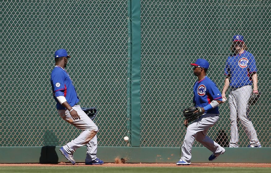 Chicago Cubs&#39; Junior Lake, left, and Arismendy Alcantara are unable to track down a ball hit by Cleveland Indians&#39; Carlos Santana as it falls between them, as Cubs&#39; pitcher Pierce Johnson, far right, looks on from the bullpenw, during the third inning of a spring training baseball game Tuesday, March 10, 2015, in Goodyear, Ariz. (AP Photo/Ross D. Franklin)