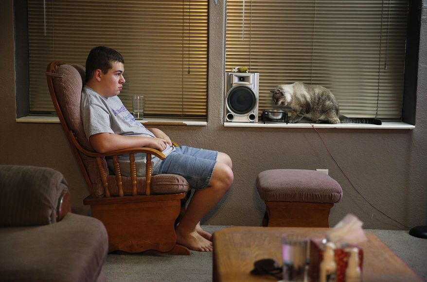In this Jan. 19, 2015, photo, Chris Cloud, 17, who suffers from Enthesitis-related arthritis, watches television at his home in Hurricane, Utah. Cloud. Chris' mother, Sarah Cloud, estimates that her family has piled up more than $12,000 in debt paying for Chris’ medication. (AP Photo/John Locher)