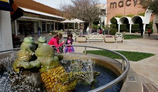 A woman and a young girl stand at a fountain at the Stanford Shopping Center, a Simon Property Group property, in Palo Alto, California. Analysts say the unsolicited $22.4 billion offer by Simon to acquire Macerich Co., reflects the attractiveness of upscale malls while more down-market properties struggle to adapt and survive. (Associated Press)