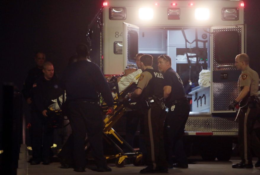 Paramedics load one of two police officers who were shot while standing guard in front of the Ferguson Police Station during a protest on Thursday, March 12, 2015. A 32-year-old officer from nearby Webster Groves was shot in the face and a 41-year-old officer from St. Louis County was shot in the shoulder, St. Louis County Police Chief Jon Belmar said at a news conference. Both were taken to a hospital, where Belmar said they were conscious. (AP Photo/St. Louis Post-Dispatch, Laurie Skrivan) EDWARDSVILLE INTELLIGENCER OUT; THE ALTON TELEGRAPH OUT