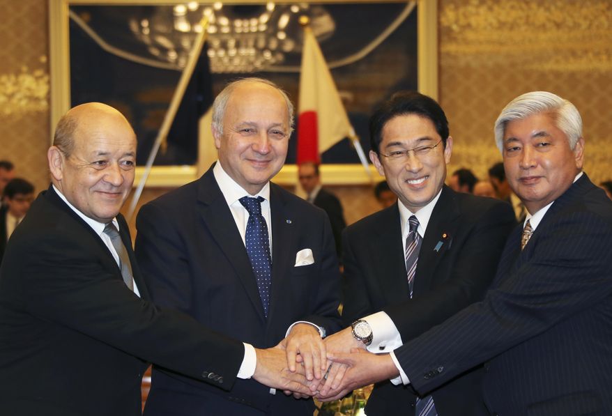 French Defense Minister Jean-Yves Le Drian, left, and French Foreign Minister Laurent Fabius, second left, join hands with Japanese Foreign Minister Fumio Kishida, seond right, and Japanese Defense Minister Gen Nakatani during a Japan-France two-plus-two meeting in Tokyo, Friday, March 13, 2015. Japan and France signed an arms transfer agreement Friday, paving the way for developing drones and other unmanned equipment together as Japan seeks to play a greater military role internationally. (AP Photo/Koji Sasahara,pool)