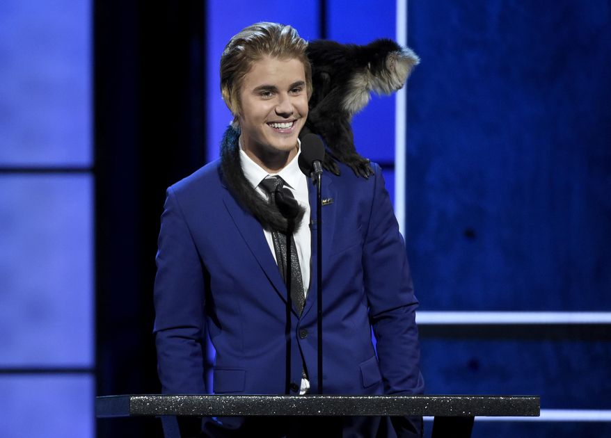 A monkey rests on Justin Bieber's shoulder as he speaks at the Comedy Central Roast of Justin Bieber at Sony Pictures Studios on Saturday, March 14, 2015, in Culver City, Calif. (Photo by Chris Pizzello/Invision/AP)