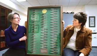 Dominique Daniel, Oakland University coordinator of university archives, left, and Shirley Paquette, archives assistant hold a display in Auburn Hills, Mich., March 10, 2015, of 50 pens used by President Lyndon Johnson to sign legislation in 1965. The pens where donated to the university by Billy Farnum, a one term U. S. Congressman.   (AP Photo/The Oakland Press, Tim Thompson)