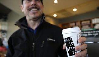 Matt Ullman holds a coffee drink with a &quot;Race Together&quot; sticker on it at a Starbucks store in Seattle, Wednesday, March 18, 2015. Starbucks CEO Howard Schultz announced earlier in the day at the company&#x27;s annual shareholder meeting that participating baristas at stores in the U.S. will be putting the stickers on cups and also writing the words &quot;#RaceTogether&quot; for customers in an effort to raise awareness and discussion of race relations. (AP Photo/Ted S. Warren)