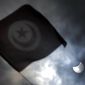 The Tunisian flag flies as the sun is seen during an eclipse in Tunis, Tunisia, Friday, March 20, 2015. An eclipse is darkening parts of the world on Friday in a rare solar event that won&#39;t be repeated for more than a decade. (AP Photo/Christophe Ena)