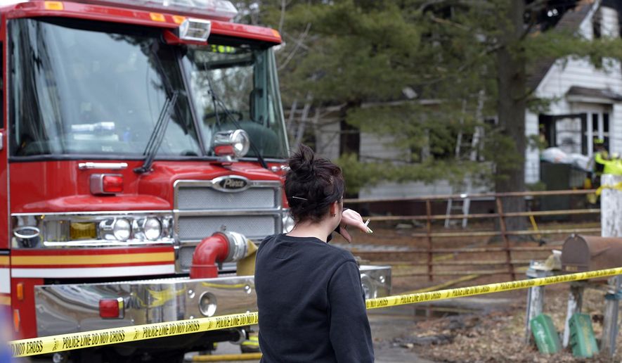 A bystander reacts as a body is removed from the fire scene in Pleasant Prairie, Wis., Thursday, March 19, 2015.  The bodies of two people have been recovered from a burned-out house on a southeastern Wisconsin farm where a couple was accused of animal neglect. (AP Photo/The Kenosha News, Brian Passino)