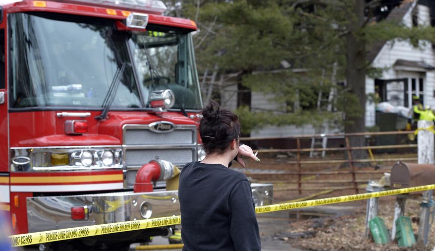 A bystander reacts as a body is removed from the fire scene in Pleasant Prairie, Wis., Thursday, March 19, 2015. The bodies of two people have been recovered from a burned-out house on a southeastern Wisconsin farm where a couple was accused of animal neglect. (AP Photo/The Kenosha News, Brian Passino)