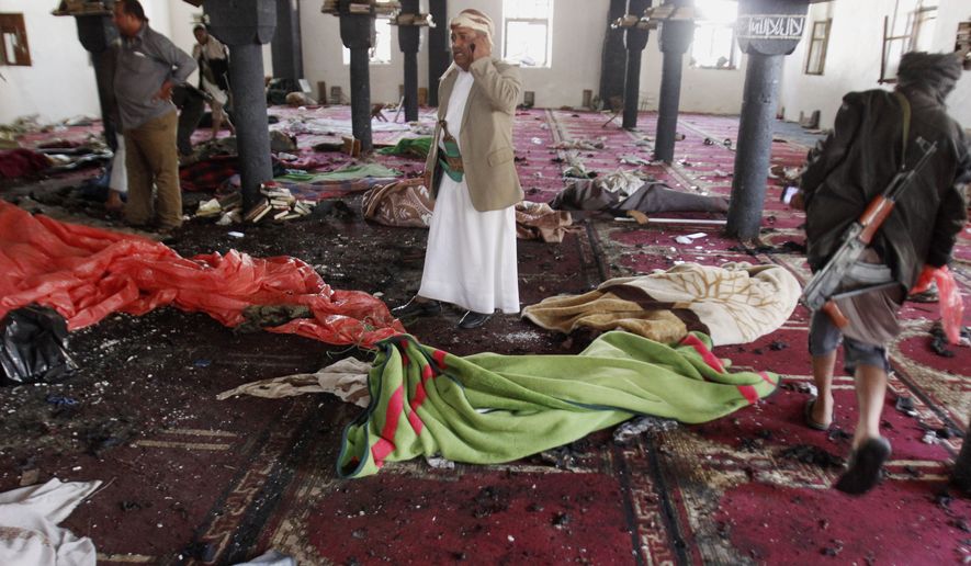 People stand amid bodies covered with blankets in a mosque after a suicide attack during the noon prayer in Sanaa, Yemen, Friday, March 20, 2015. (AP Photo/Hani Mohammed)