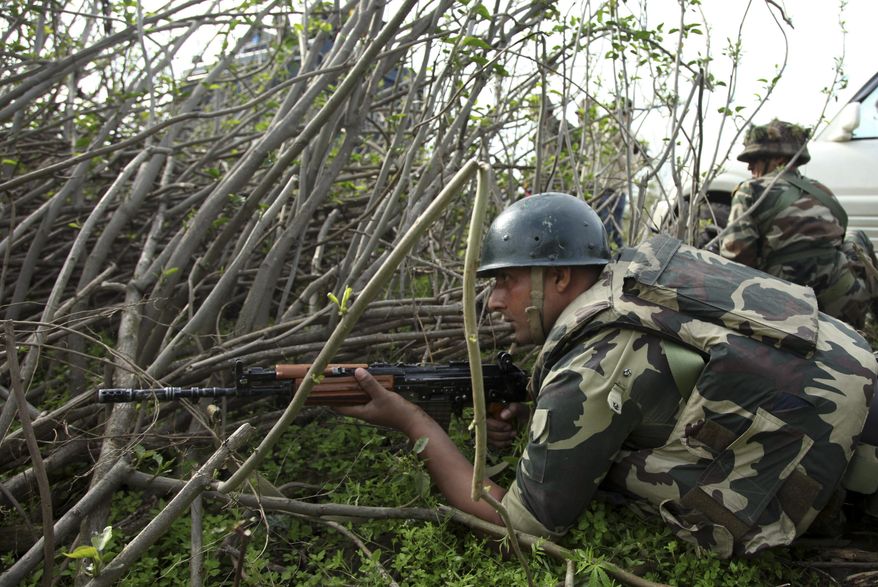 Indian paramilitary soldiers take position as they watch a gun battle between suspected militants and security forces in Kathua district, about 80 kilometers (50 miles) south of Jammu, India, Friday, March 20, 2015. Suspected rebels wearing army uniforms stormed an Indian police station in Kashmir, sparking a four-hour gun battle near the border between Indian- and Pakistani-controlled parts of the disputed Himalayan region. (AP Photo/Channi Anand)