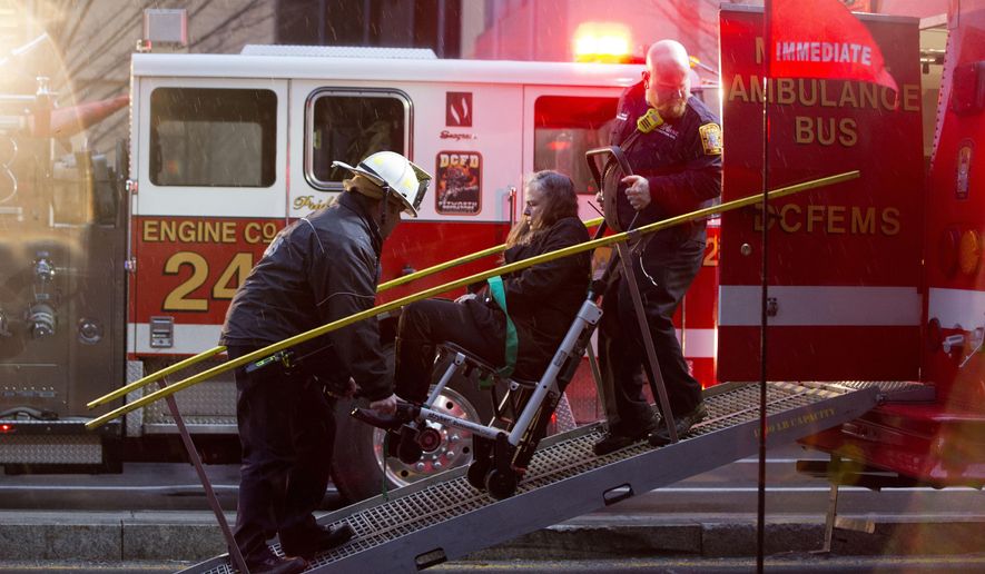 FILE - In this Jan. 12, 2015 file photo, a woman is transported in a wheelchair onto an ambulance as people are evacuated from a smoke filled Metro subway tunnel in Washington. A policy of routing calls about emergencies on the Metro subway system directly to a supervisor at the District of Columbia’s 911 call center contributed to delays in getting firefighters to the scene of an accident that turned deadly, officials say. (AP Photo/Jacquelyn Martin, File)