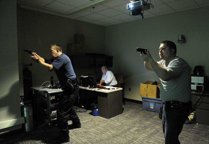 In a March 18, 2015 photo, Pat Schneider, left, and Kevin Ingrody, both officers with the Garden City Police Dept., train using a simulator that displays real life scenarios, in Livonia, Mich. Schoolcraft College course instructes police officers on simulators in a "Shoot-Don't shoot" scenario designed to train officers with help of MCOLES grants. The Michigan Commission on Law Enforcement Standards recently announced it won't accept competitive grant applications, which typically reflect 40 percent of funds provided for overall officer training, for next year. (AP Photo./The Detroit News, Clarence Tabb Jr.)