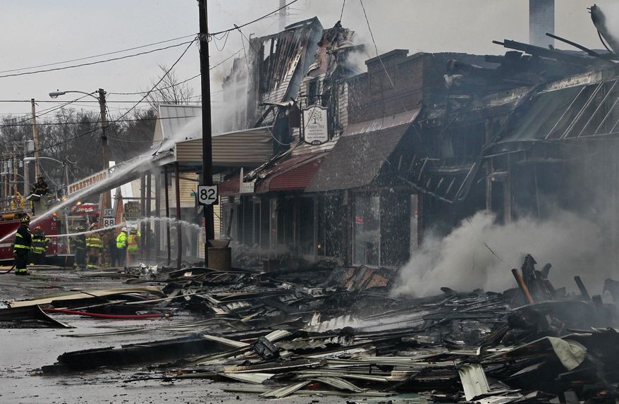 FILE - In this Saturday, March 22, 2014 file photo, severely damaged buildings smolder as firefighters from several area fire departments work to bring a fire at the intersections of High and Water Streets in downtown Garrettsville under control in Garrettsville, Ohio. Officials and residents of Garrettsville say they're still trying to rebuild after a downtown fire destroyed several buildings a year ago. (AP Photo/Akron Beacon Journal, Ed Suba Jr., File) MANDATORY CREDIT