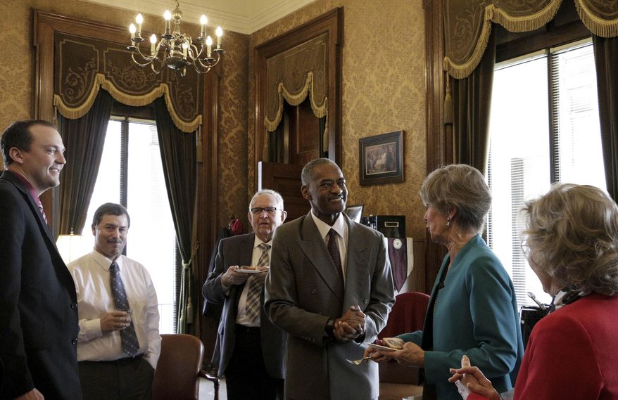 Washington State University President Elson Floyd, center, meets with lawmakers following the passage of a bill that opens the door for the college to open a medical school in Spokane, Wash., on Wednesday, March 25, 2015, in Olympia, Wash. The bill eliminates a restriction dating from 1917 that gives the University of Washington in Seattle the exclusive right to operate a public medical school in the state.(AP Photo/Rachel La Corte)