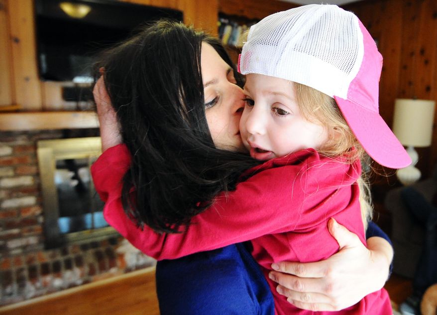 In this Feb. 21, 2015 photo, Cara O'Neill, left, gives a kiss to her daughter, Eliza, 5, at their home in Columbia, S.C. Glenn and Cara O'Neill started the Cure Sanfilippo Foundation in hopes of saving Eliza, who suffers from the rare disease and is beginning to lose her ability to speak. The disease kills brain cells, causing hyperactivity and autistic-like behavior, then seizures, loss of ability to walk and usually death by the mid-teens. "The next six or seven years will be horrible for her, and then she'll die," her father said. (AP Photo/Rainier Ehrhardt)