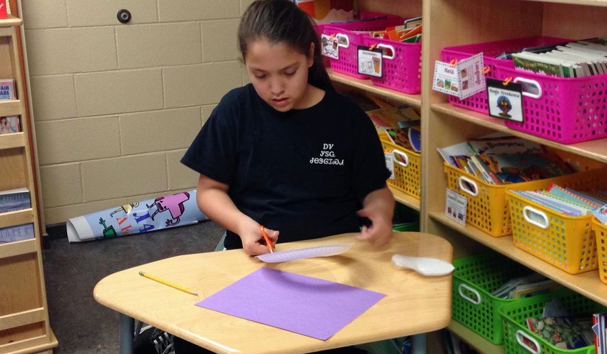 In this Wednesday, Feb. 11, 2015 photo, Cherokee tribe member Haley Smith, 11, works on an English assignment at New Kituwah Academy in Cherokee, N.C. On this particular day, Haley and her classmates were learning about idioms related to Valentine’s Day. With fewer than 300 native Cherokee speakers remaining in North Carolina, tribe members hope to preserve their language and culture through the small school where their children are immersed in their people’s native tongue. (AP Photo/Martha Waggoner)