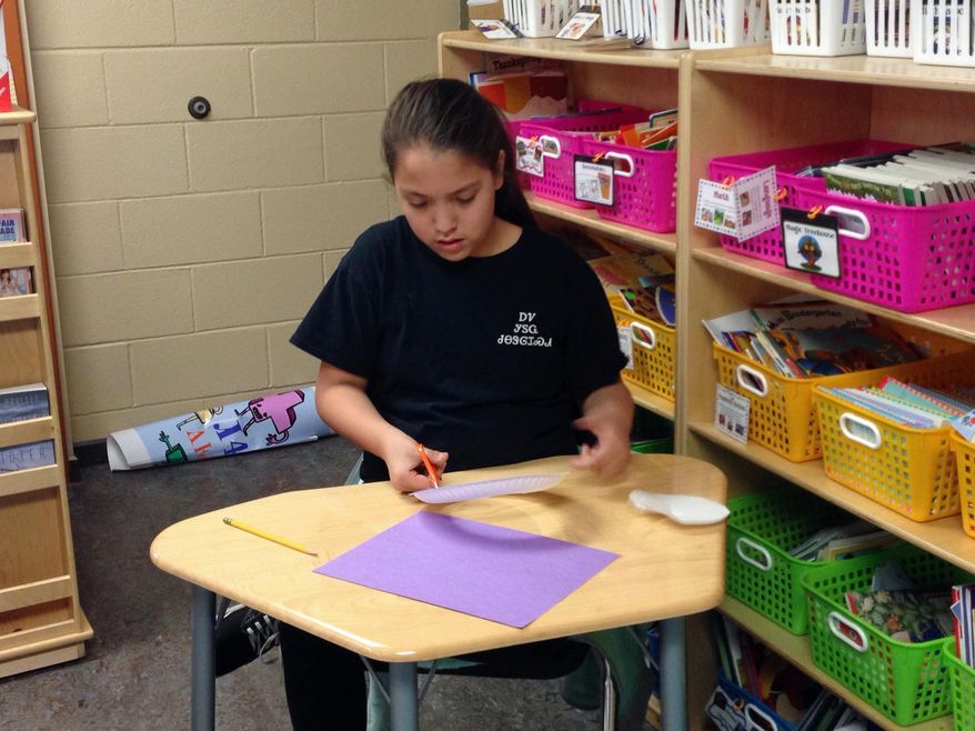 In this Wednesday, Feb. 11, 2015 photo, Cherokee tribe member Haley Smith, 11, works on an English assignment at New Kituwah Academy in Cherokee, N.C. On this particular day, Haley and her classmates were learning about idioms related to Valentine’s Day. With fewer than 300 native Cherokee speakers remaining in North Carolina, tribe members hope to preserve their language and culture through the small school where their children are immersed in their people’s native tongue. (AP Photo/Martha Waggoner)