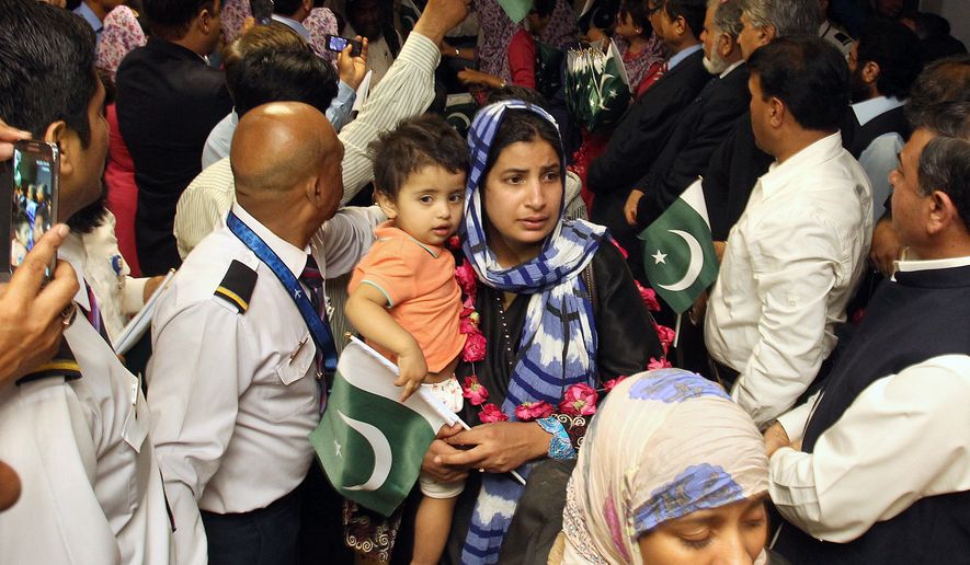 Pakistani families, evacuated from Yemen, are greeted by Pakistani airline staff upon their family arrival in Jinnah International Airport in Karachi, Pakistan on Monday, March 30, 2015. Pakistan evacuated some 500 of its citizens by a special plane from Yemeni city of Hodeida. Pakistan says some 3,000 of its citizens live in Yemen. (AP Photo/Fareed Khan)