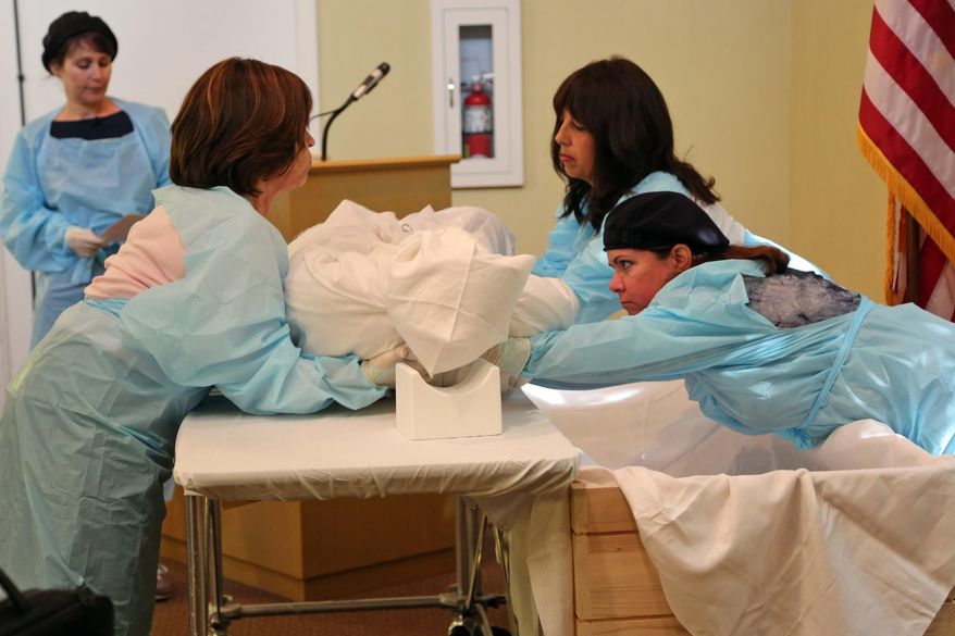 Members of the Boca Raton Synagogue Chevra Kadisha, from left; Dana Petrover, Yvette Kaweblum, Cheryl Mirsky and Dana Schechter give a demonstration on the proper way to wrap a body and move it to a Kosher casket for burial during a presentation at Levitt-Weinstein Funeral Home in Coconut Creek on Monday, March 16, 2015. Students from Weinbaum Yeshiva High School in Boca Raton are visiting the funeral home to learn about Jewish death rituals. (AP Photo/South Florida Sun Sentinel, Amy Beth Bennett)