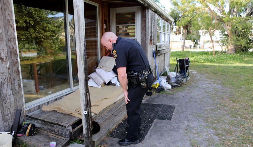 ADVANCE FOR WEEKEND EDITIONS, APRIL 4-5 - In this photo taken on Feb. 25, 2015, Clearwater Police officer Eric Mitchell examines a known homeless squatting site on an abandoned property in Clearwater, Fla. As a teenager, Mitchell used to stand in lines at food pantries and lived in a car for a year, but eventually got off the streets. he hopes he can help others to do the same in his new role on the Clearwater Police Department's bike team, which primarily focuses on homeless outreach. (AP Photo/The Tampa Bay Times, Douglas R. Clifford) TAMPA OUT; CITRUS COUNTY OUT; PORT CHARLOTTE OUT; BROOKSVILLE HERNANDO TODAY OUT