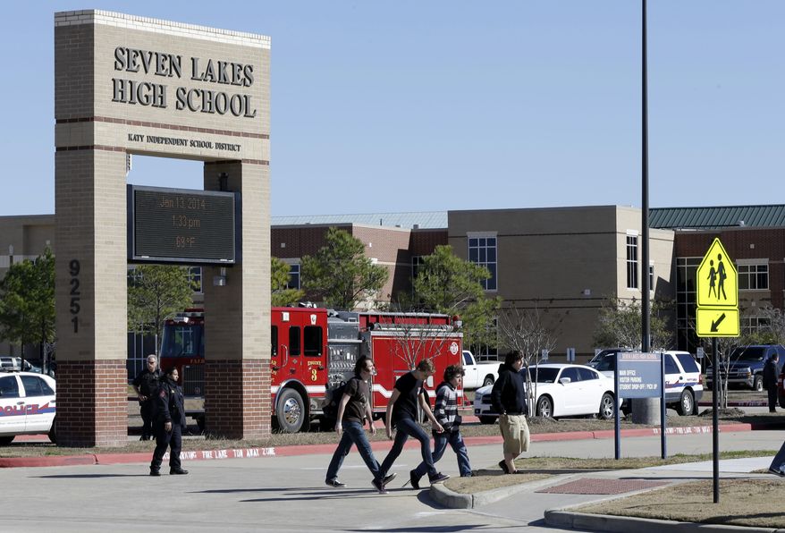 In this Jan. 13, 2014, file photo, students pass by Seven Lakes High School after being evacuated and released from school for the day after a bomb squad was called to the school after a potentially explosive device was found. Threats against schools don’t just come written on bathroom walls these days. Spread using smart phone apps, social media and Internet phone services, anonymous reports of bombs or other threats of violence are forcing school evacuations and a response by police swat teams or other authorities to what in the vast majority of cases turns out to be a hoax. (AP Photo/Pat Sullivan, File)