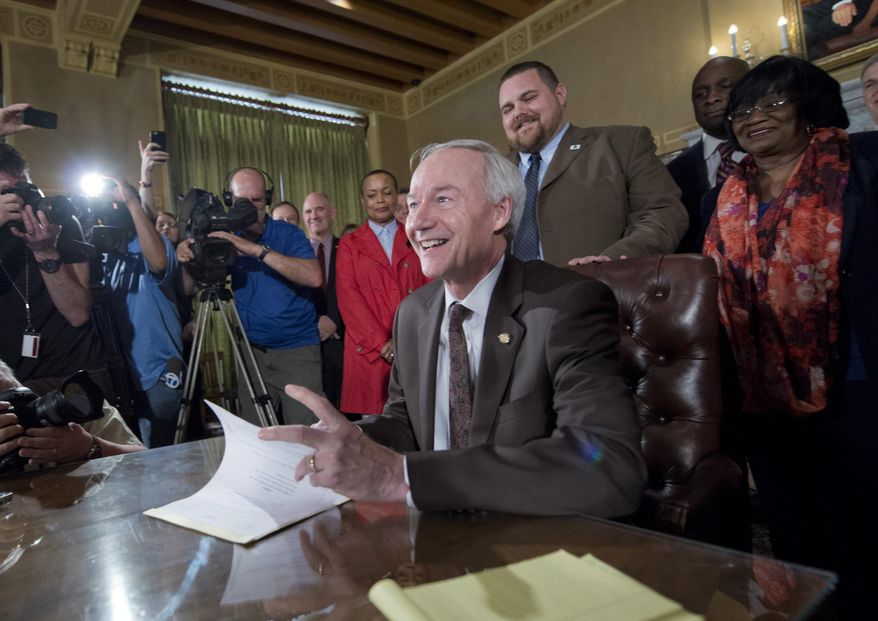 Arkansas Gov. Asa Hutchinson signs a reworked religious freedom bill into law after it passed in the House at the Arkansas state Capitol in Little Rock, Ark., Thursday, April 2, 2015. (AP Photo/Brian Chilson)