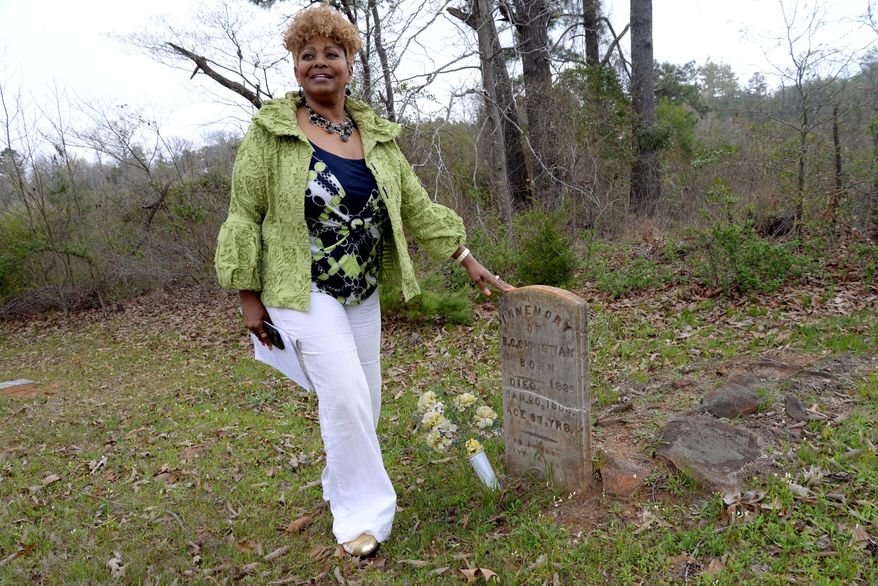 ADVANCE FOR USE MONDAY, APRIL 6 - In this photo taken Tuesday, March 24, 2015, Debra Christian stands next to her great grandfather B.C. Christian's tombstone that overlooks 14-wooded acres she plans on building homes for homeless veterans in White Oak, Texas. (AP Photo/The News-Journal, Kevin Green)