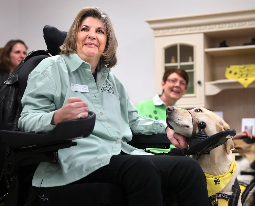 Jill Jensen smiles as her assistance dog Linden looks at her during a ceremony marking the grand opening of the K9s 4 Mobility Colter Allen Training Facility off Campstool Road in Cheyenne, Wyo. (AP Photo/Wyoming Tribune Eagle, Michael Smith)