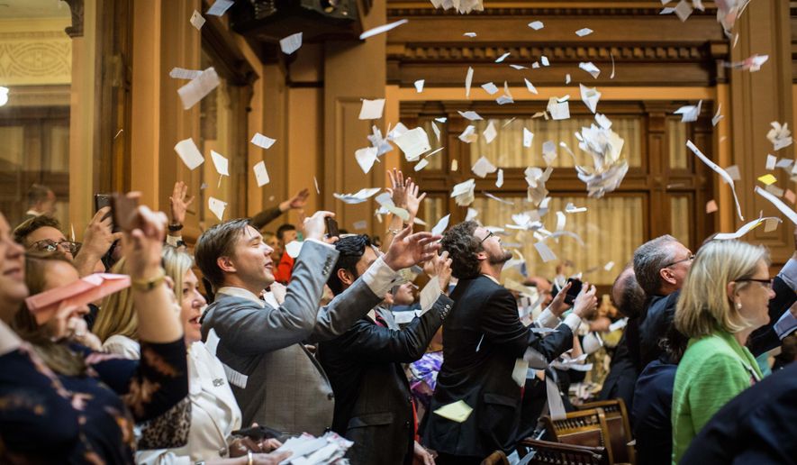 House members throw up paper at the conclusion of the legislative session in the House Chamber, Friday, April 3, 2015, in Atlanta. By law, Georgia's General Assembly meets for 40 working days each year. Any bills not approved by each chamber by midnight are dead for the year. (AP Photo/Branden Camp)