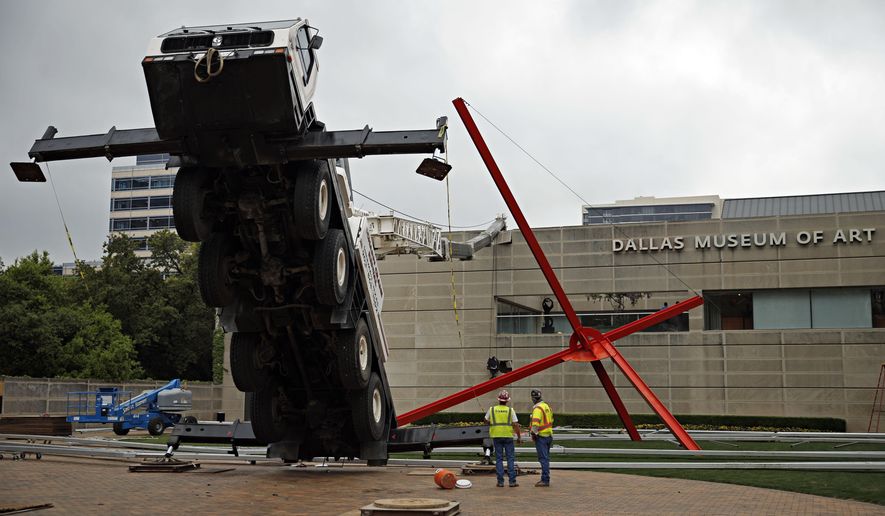 Workers look on at a collapsed crane in front of the Dallas Museum of Art, Friday, April 3, 2015 in Dallas. The truck-mounted crane has toppled onto the roof of the Dallas Museum of Art, injuring the operator and narrowly missing a sculpture outside the building. (AP Photo/The Dallas Morning News, G.J. McCarthy) MANDATORY CREDIT; MAGS OUT; TV OUT; INTERNET USE BY AP MEMBERS ONLY; NO SALES