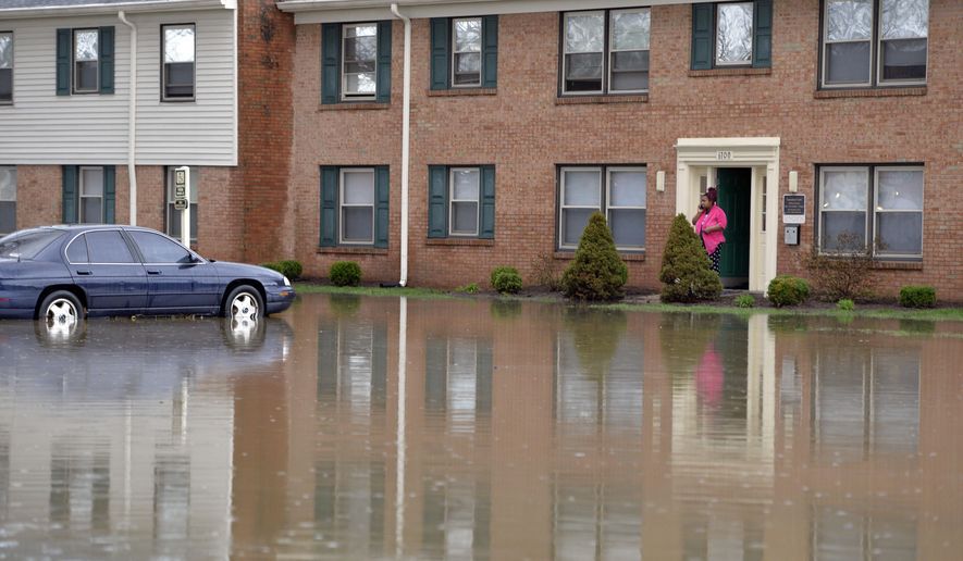 Simone Wester talks with family on the phone from the front door of her apartment building at the Guardian Court Apartments in Louisville, Ky., Friday, April 3, 2015. More than a foot of water flooded the apartment complex. Authorities in Louisville, Kentucky, made more than 100 water rescues early Friday as area storms flooded roads and prompted at least one evacuation. (AP Photo/Timothy D. Easley)