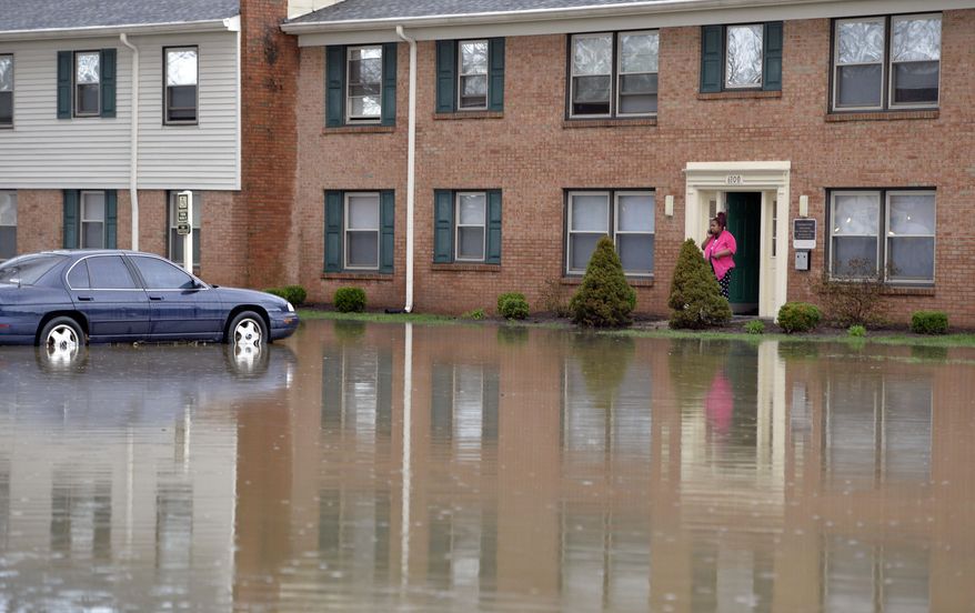 Simone Wester talks with family on the phone from the front door of her apartment building at the Guardian Court Apartments in Louisville, Ky., Friday, April 3, 2015. More than a foot of water flooded the apartment complex. Authorities in Louisville, Kentucky, made more than 100 water rescues early Friday as area storms flooded roads and prompted at least one evacuation. (AP Photo/Timothy D. Easley)
